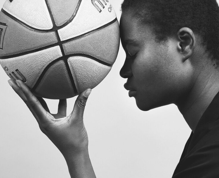 frau hält basketball an stirn