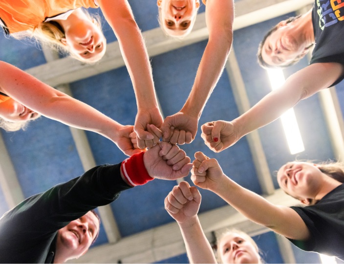 Sportlerinnen strecken Hände in die Mitte MentalWin