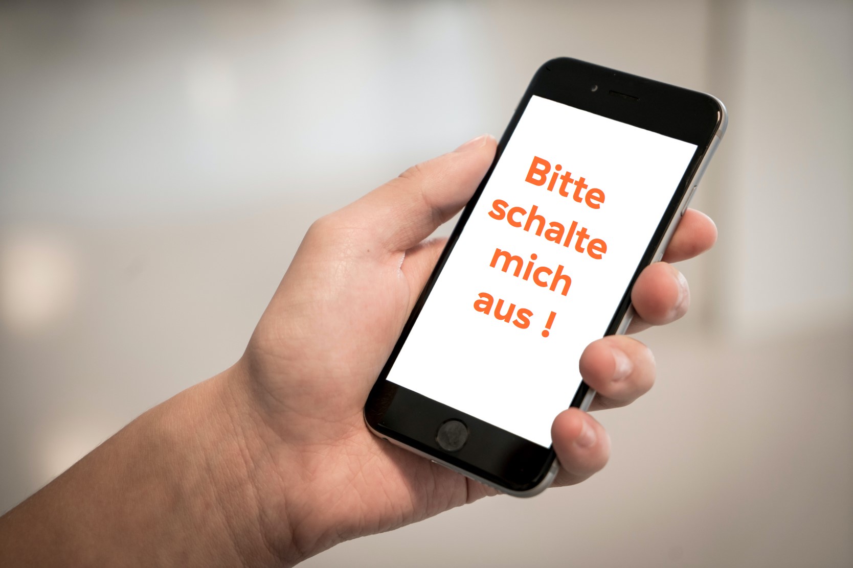 Handy in der linken Hand mit Aufschrift: bitte schalte mich aus