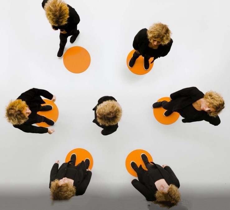 6 Personen stehen im Kreis und eine Person in der Mitte