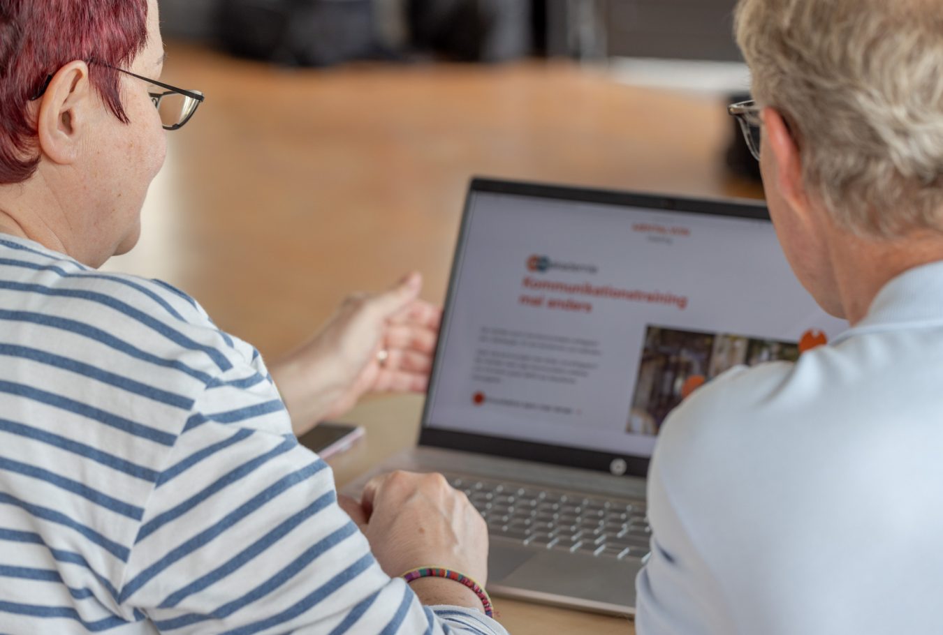 Eine Frau, ein Mann schauen sich eine Internetseite im Laptop an