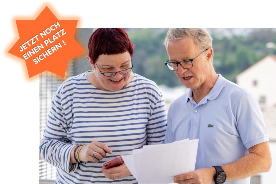 Mann und Frau schauen gemeinsam auf DinA4 Blätter. Frau tippt in ihr Handy.